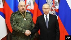 Presiden Rusia Vladimir Putin berjabat tangan dengan wakil komandan operasi militer Rusia di Ukraina Jenderal Sergei Surovikin, saat ia dianugerahi medali "Saint George" di markas besar Distrik Militer Selatan, Rusia, Sabtu, 31 Desember 2022.