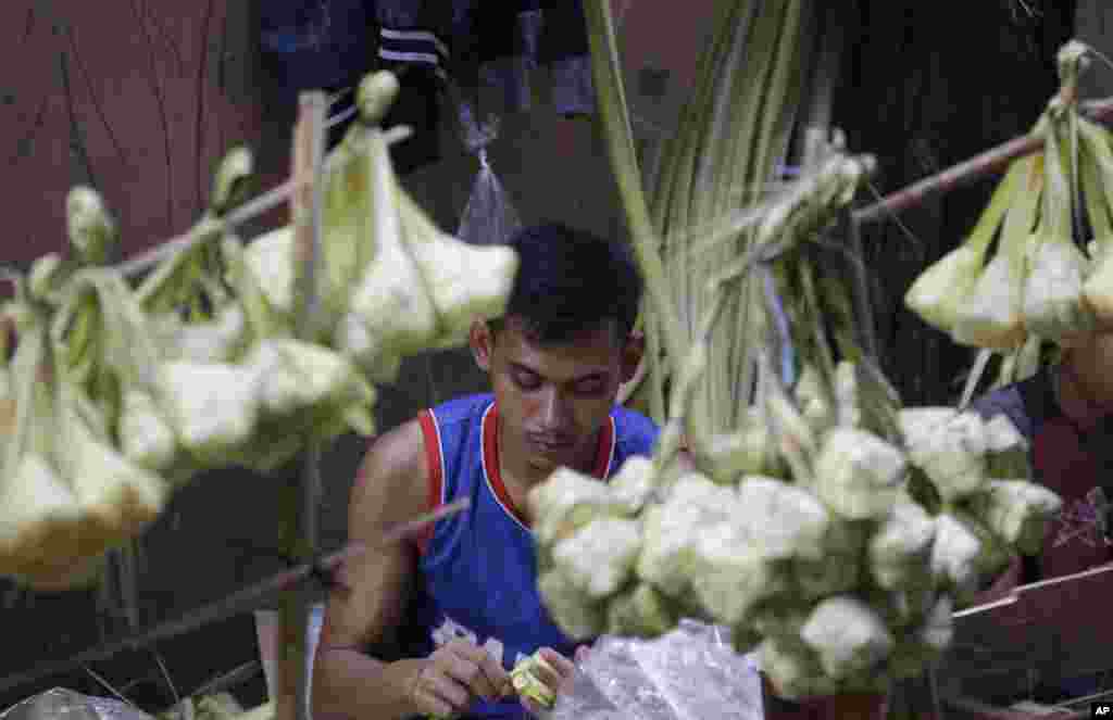 Seorang pedagang membuat kulit ketupat sambil menunggu pelanggan menjelang Idul Fitri di Jakarta, Selasa, 4 Juni 2019. (Foto: AP)