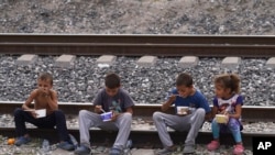 FILE - Migrant children eat sitting on railroad tracks as they wait to board a northbound freight train, in Huehuetoca, Mexico, May 12, 2023.