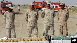 FILE - Iranian police officers stand behind narcotics that were seized at the Milak border in southeastern Iran, Oct. 10, 2012.