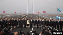 2026년 10월 24일 김정은 북한 국무위원장의 중국 랴오닝성 단둥 방문 중, 김정은 위원장과 왕후닝 중국 인민정치협상회의(정협) 전국위원회 의장, 왕이 중국 외교부장, 최선희 북한 외무상이 중국 단둥과 북한 신의주를 잇는 신압록강대교에서 관계자들과 함께 기념사진을 찍고 있다.