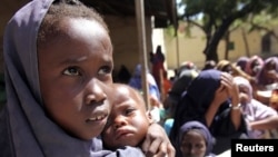 An internally displaced Somali girl carries her sibling as they wait to collect food relief from the World Food Program (WFP) at a settlement in Mogadishu August 7, 2011.