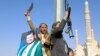 Protesters, one holding a portrait of Huthi leader Abdul Malik al-Houthi (L), brandish their weapons during a protest following US and British forces strikes, in the Huthi-controlled capital Sanaa on January 12, 2024 amid the ongoing battles between Israe