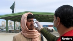 FILE - A health worker takes the temperature of a Afghan national at the Chaman crossing point on the Pakistan-Afghanistan border, in Chaman, Pakistan, Feb. 26, 2020.