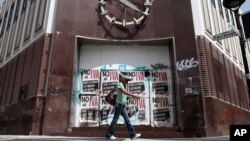 A woman walks in front of a closed bank in the neighborhood of Rio Piedras in San Juan, Puerto Rico, June 29, 2015. 