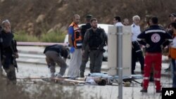 An Israeli officer inspects the body of a Palestinian man at a checkpoint near Nablus, Oct. 30, 2015. Israeli police said two Palestinians ran toward the checkpoint with knives in their hands, drawing Israeli fire that killed one and wounded the other.