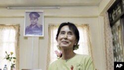 Pro-democracy leader Aung San Suu Kyi pauses during an interview with the Associated Press as a portrait of her father, independence hero Gen. Aung San, hangs on the wall at the National League for Democracy headquarters in Rangoon, Burma, 18, Nov. 2010.