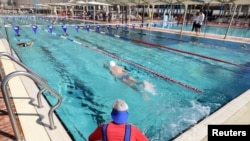 People swim at a pool where a 'Green Badge' is required to enter, as Israel reopens swathes of its economy, continuing to lift restrictions of a national lockdown to fight COVID-19, at Gordon Gym and Pool in Tel Aviv, Feb. 21, 2021.