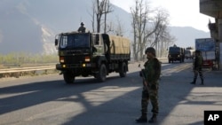 An Indian army soldier stands guard as an army convoy moves on a highway on the outskirts of Srinagar, Indian-controlled Kashmir, Feb. 7, 2019.