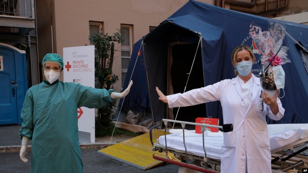 Monica Carfora, right, deputy head of the emergency of the Santo Spirito Hospital poses for a photograph with nurse Silvia Sforza, holding out their arms to indicating social distancing in Rome, April, 12, 2020. 