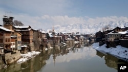 Rumah-rumah yang tertutup salju berdiri di tepi Sungai Jhelum di Srinagar, Kashmir yang dikuasai India, Jumat, 8 Februari 2019.