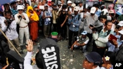 An activist of Cambodian National Rescue Party Meach Sovannara, center, gives a speech as he is surrounded by local journalists at a blocked main street near the Phnom Penh Municipality Court during a gathering to call for the release of anti-government protesters who were arrested in a police crackdown, in Phnom Penh, May 20, 2014. 