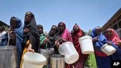 FILE: Displaced Somali girls who fled the drought in southern Somalia stand in a queue to receive food handouts at a feeding center in a camp in Mogadishu. Taken March 4, 2017
