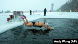 A woman jumps into a pool cut from the ice on the Songhua River in Harbin in northeastern China's Heilongjiang province, Tuesday, Jan. 7, 2025. (AP Photo/Andy Wong)