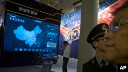 FILE - Visitors look at a display of information technologies at an exhibition highlighting China's achievements under President Xi Jinping's leadership, at the Beijing Exhibition Hall in Beijing, China, Oct. 17, 2017.