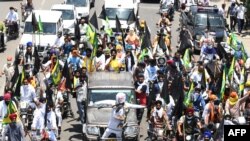 Para petani membawa bendera hitam mengendarai sepeda motor, mengiringi mobil yang menampilkan patung Perdana Menteri India Narendra Modi, dalam unjuk rasa 'Hari Hitam' menandai enam bulan aksi protes reformasi pertanian di Amritsar, India, 26 Mei 2021. (NARINDER NANU / AFP)