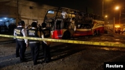 Peruvian police officers work next to a burnt bus on a street in Lima, Peru, March 31, 2019. 