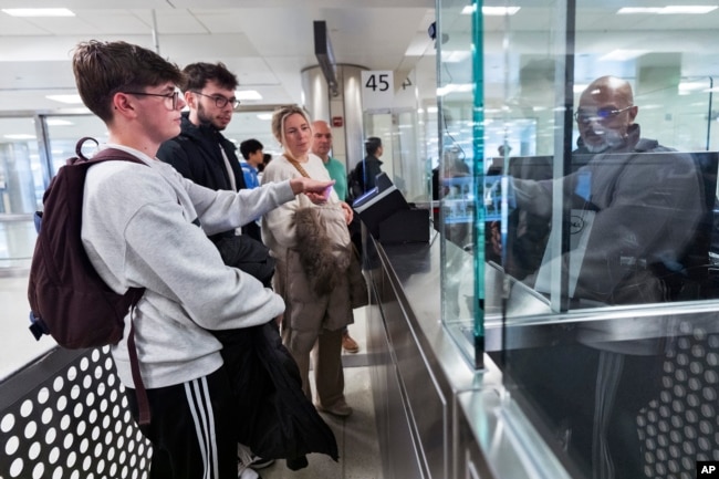 Piet De Staercke, his wife Jill Bornauw, and their eldest son Stan De Staercke watch their youngest Tuur de Staercke, get screened by a Customs Border Protection officer at Washington Dulles International Airport in Virginia, April 1, 2024. (AP Photo/Manuel Balce Ceneta)