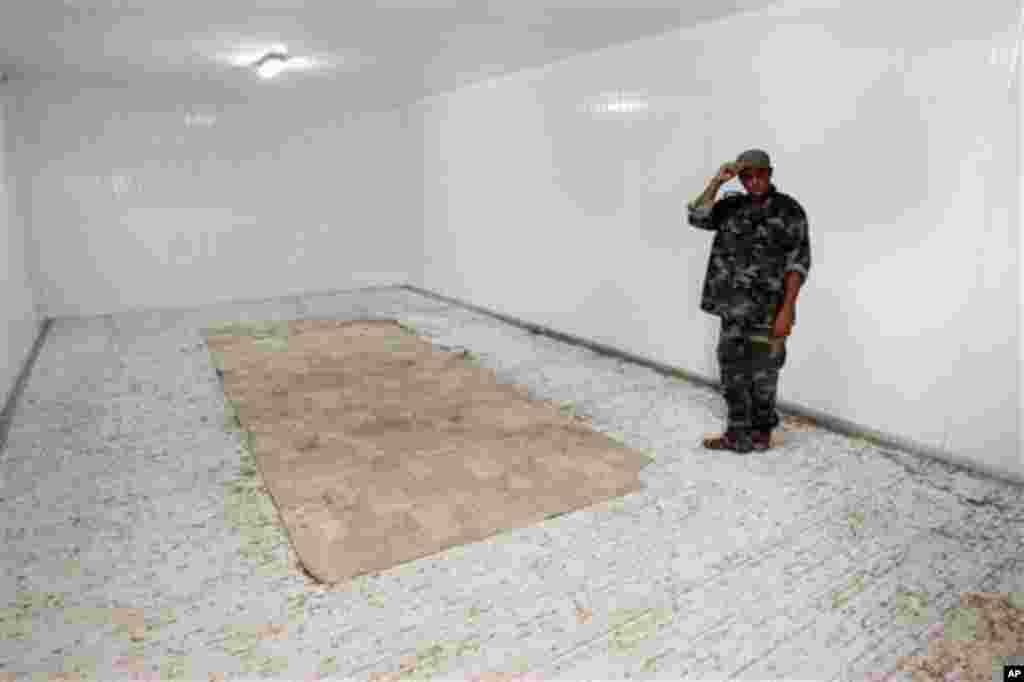 2011年10月25日 一名利比亞反卡扎菲戰士站在冰庫內。卡扎菲的屍體曾在這裡陳列。(美聯社)