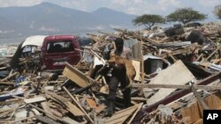 Un agente de policía carga con un perro rastreador de la unidad K9 durante la operación de búsqueda de víctimas del terremoto y tsunami en Palu, en la isla indonesia de Célebes, el 3 de octubre de 2018.