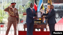 Presiden Kenya William Ruto menyerahkan konstitusi Kenya kepada Wakil Presiden Kithure Kindiki setelah ia mengambil sumpah jabatan dalam upacara pelantikannya, 1 November 2024.