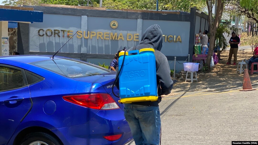 Trabajadores desinfectan vehículos frente al edificio de la Corte Suprema de Justicia de Niaragua en Managua.