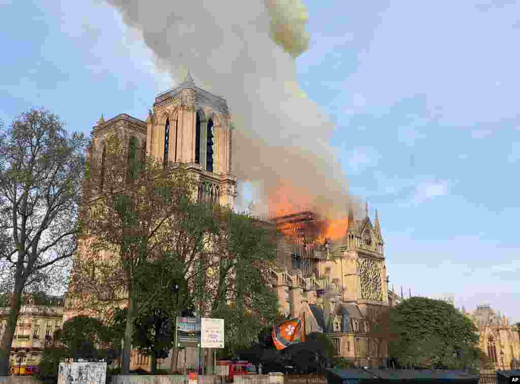 Notre Dame cathedral is burning in Paris, April 15, 2019. Massive plumes of yellow brown smoke is filling the air above Notre Dame Cathedral and ash is falling on tourists and others around the island that marks the center of Paris. 