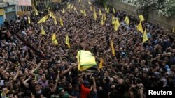 Anggota kelompok Hizbullah mengangkat peti mati yang membawa jenazah komandan militer mereka, Mustafa Badreddine, ke tempat pemakaman di kawasan sub-urban selatan Beirut, Lebanon (13/5). 