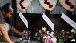 Jamila McNichols, hermana de Thomas "TJ" McNichols, quien murió en el tiroteo del 4 de agosto en Dayton, Ohio, deja una foto y flores junto a un altar en honor de las víctimas, cerca del lugar del ataque. Lunes 5 de agosto de 2019. (Foto AP / John Minchillo)