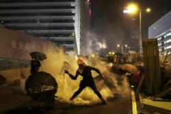 A protester throws a tear gas canister which was fired by riot police during a rally in Hong Kong, July 28, 2019.