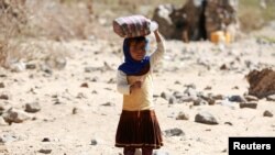 Une petite fille porte de l'eau dans un camp de réfugiés entre Marib et Sanaa, Yémen, le 29 mars 2018