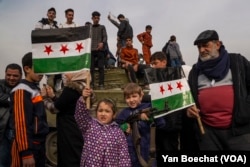 A child holds an AK-47 of one of the rebels of jihadist group Hayat Tahir al-Sham that stormed Damascus putting an end to the regime of Bashar al-Assad, Dec. 12, 2024.