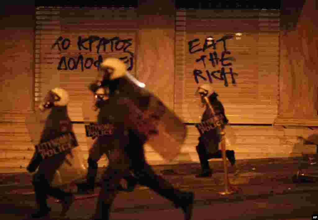 Riot police chase protesters in front of a hotel during a protest in Athens after a Greek retiree shot himself, April 4, 2012. (AP) 