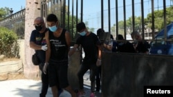 FILE - Plainclothes police officers escort four migrants who are detained as suspects for a fire that burned the Moria camp for refugees and migrants, on the island of Lesbos, Greece, Sept. 16, 2020. 