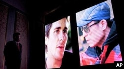 A man stands near a screen as photos of British actor Christian Bale, left, and Chinese director Zhang Yimou, right, are shown during a press conference to promote Zhang's new movie in Beijing, China, 22 Dec 2010.