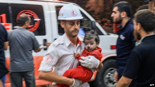 A Palestinian paramedic carries a child injured in an Israeli air strike at the Nasser hospital in Khan Yunis in the southern of Gaza Strip, on Oct. 17, 2023.