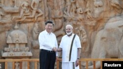 Presiden China Xi Jin-ping (kiri) dan PM India Narendra Modi berjabat tangan saat mengunjungi monumen kuno di kota Mamallapuram, India selatan hari Jumat (11/10). 