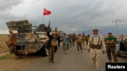 Shi'ite fighters are on the move in the town of Hamrin in Salahuddin province, March 3, 2015. Wearing military fatigues and a white turban, Shi'ite cleric Sheikh Ahmed al-Rubaei gave an eve-of-battle address to Iran-backed fighters preparing to attack IS.