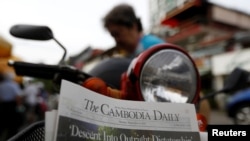 FILE - A woman buys the final issue of The Cambodia Daily newspaper at a store on a street in Phnom Penh, Cambodia, Sept. 4, 2017. 