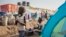 FILE - A young displaced girl washes clothes alongside a row of tents in the United Nations camp in Juba, South Sudan. Since December, over a million people in the country have been displaced by fighting. (AP) 