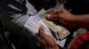Un venezolano verifica sus billetes de bolívares y dólares en las calles de Caracas, en marzo de 2022. El gobierno descarto este jueves un anuncio de aumento del salario mínimo mensual en los próximos días.