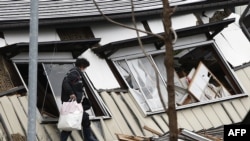 Un résident de Hakubadans la préfecture de Nagano, marche devant les débris d'un bâtiment, 23 novembre 2014.