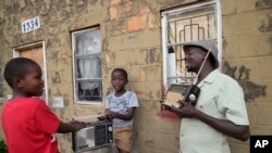 FILE - Ngwiza Khumbulani Moyo, a vintage collector, shows young boys some of his old radio sets outside his home in Bulawayo, Zimbabwe, Feb. 15, 2023.