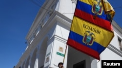 Un hombre ondea las banderas nacionales de Ecuador frente al palacio presidencial después de que el presidente Guillermo Lasso, disolviera la Asamblea Nacional por decreto el 17 de mayo de 2023.