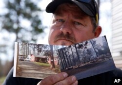 FILE - Bill Husa holds before-and-after photos of his home, Oct. 24, 2019, lost in the Camp Fire in Paradise, Calif. Husa's home is one of nearly 9,000 Paradise homes destroyed in the deadliest and most destructive wildfire in California history.