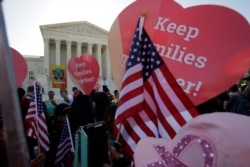 FILE - Activists rally at the U.S. Supreme Court as justices hear arguments in a challenge to then-President Barack Obama's executive action to defer deportation of certain undocumented children and parents, in Washington, April 18, 2016.