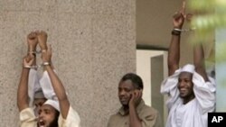 Three of four Islamists (excluding man in center) accused in 2008 killing of US diplomat and his Sudanese driver, raise their hands and shout slogans as they walk out of a Sudanese court in Khartoum (24 Jun 2009 file photo)