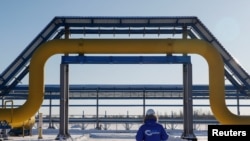 Seorang pekerja berjalan melewati bagian dari jalur gas milik perusahaan Rusia Gazprom di stasiun Atamanskaya di luar Kota Svobodny, Rusia, pada 29 November 2019. (Foto: Reuters/Maxim Shemetov)