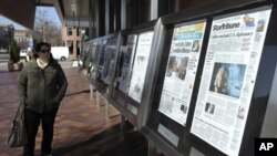 A woman reads the front pages of U.S. newspapers outside the Newseum in Washington.