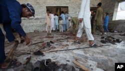 Pakistani villagers clean the floor of a mosque targeted by a suicide attacker in the Pakistani tribal area of Khyber, Aug. 19, 2011.